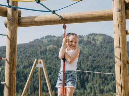 Mädchen balanciert an einem Kletterelement auf dem Abenteuerspielplatz