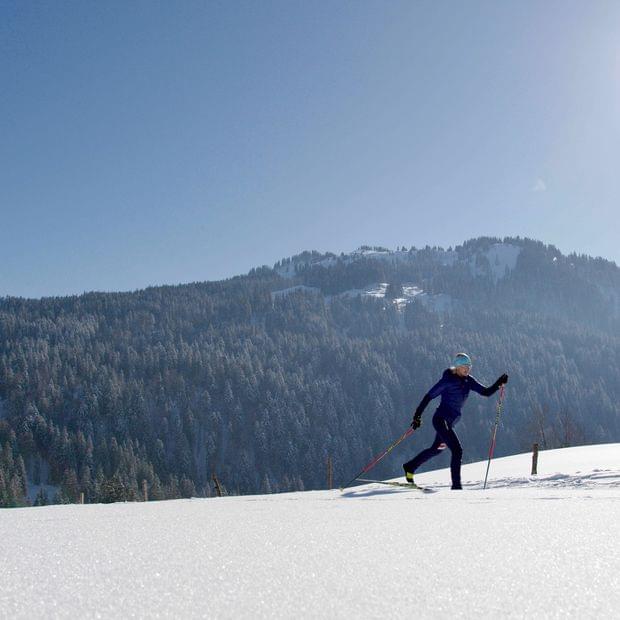 Torghele's Wald + Fluh - Winterurlaub im Allgäu - Frau beim Langlaufen bei Sonnenschein