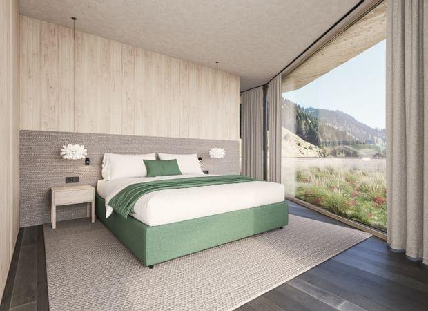 Schlafzimmer mit großem Bett in Grün-Weiß, Nachttischen und weitem Panoramablick ins Tal.