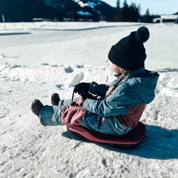 Kind sitzt auf Rodel im Allgäu - Familienhotel Allgäu Torghele's Wald + Fluh
