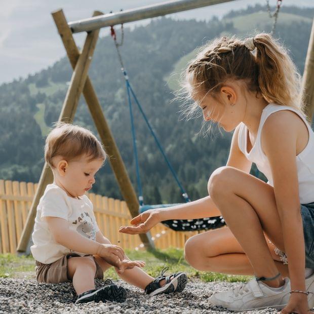 Zwei Kinder spielen gemeinsam im Kiesbereich des Abenteuerspielplatzes