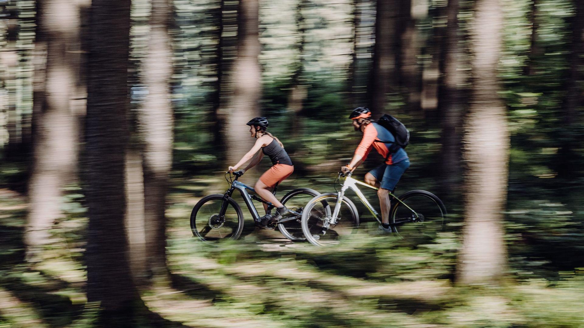 Zwei Radfahrer unterwegs beim Bikeurlaub im Allgäu durch den Wald.