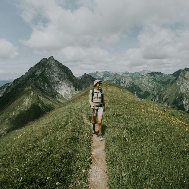Eine Person wandert auf einem Berggrat beim Wanderurlaub im Allgäu.